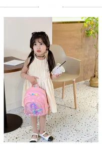 Toddler girl wearing pink mermaid backpack with pom-poms in a cozy cafe setting