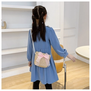 Detail of child wearing straw crossbody bag with pink lace bow and white pearl accents