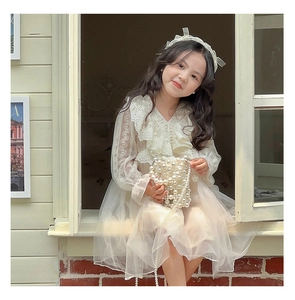 Close-up of elegant white lace dress with layered tulle sleeves and ruffled collar