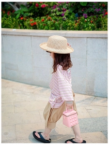 Pink quilted crossbody bag for kids styled with a straw hat and casual summer outfit