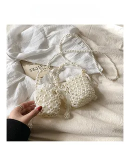 Detail shot of a handmade woven pearl mini bag featuring a satin ribbon and chain strap