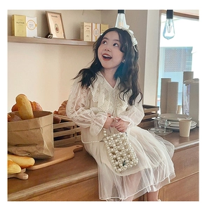 Detail of a white lace mesh princess dress with pearl crossbody bag for little girls