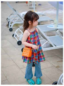 Girl's stylish outfit featuring an orange silicone rivet bag and plaid top by the pool