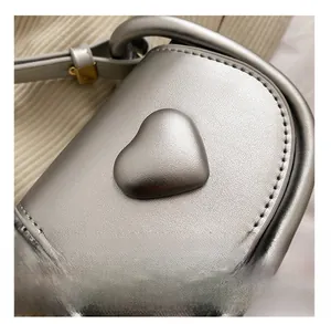 Detail shot of silver faux leather mini bag with heart decor and pebbled texture