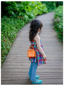 Detailed outdoor shot of orange mini quilted bag with twist handle and metal chain strap