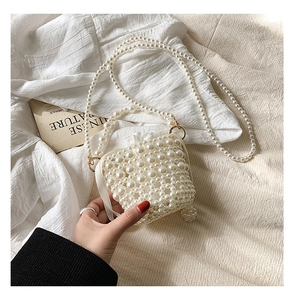 Detail view of mini pearl beaded bag with gold hardware and white drawstring liner