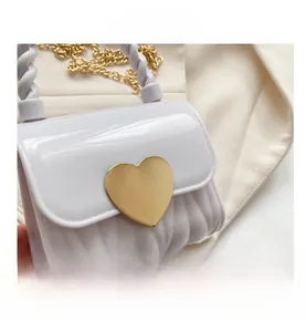 Detail der weißen Jelly-Tasche mit goldener Herzschnalle und gesteppter Wellenstruktur