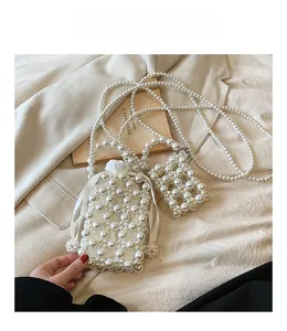 Detail of hand-woven pearl crossbody bag with drawstring liner and mini charm pouch