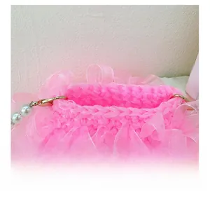 Nahaufnahme der rosa handgewebten Tasche mit Organza-Rüschen und weißer Perlenkette