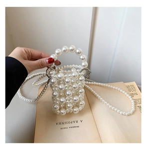 Detailed view of woven pearl crossbody bag with silver metal buckles on a vintage book