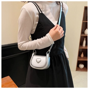 Mini silver crossbody bag with a 3D heart detail on the flap shown on a model