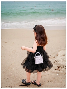 Mini lavender crossbody bag with quilted rivet detail on a child at the beach