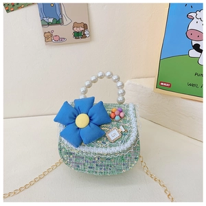 Détail du sac fille en tweed vert avec poignée en perles et fleur en tissu bleu