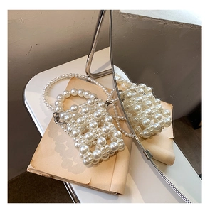 Detail of woven faux pearl handbag with rectangular cutout structure and pearl chain strap