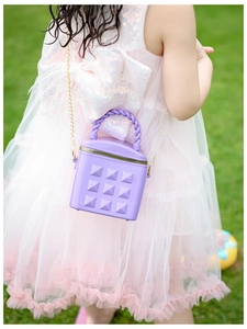 Detail view of a purple studded mini bag for girls with golden chain strap on green grass