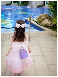 Detail of purple mini quilted bag with gold chain strap on a girl in a tulle dress