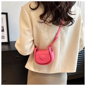 Vue détaillée du mini sac bandoulière rose fuchsia à cœur porté par un enfant sur un blazer
