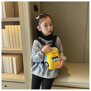 Vue détaillée du sac à dos bus jaune porté par une petite fille assise dans une bibliothèque