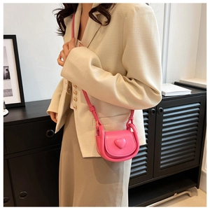 Mini pink heart crossbody bag shown with outfit to demonstrate its small size and style