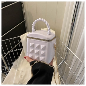 Close-up of a white mini square bucket bag with embossed quilted texture and gold chain