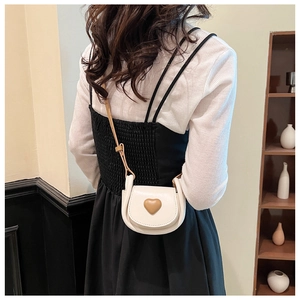 Vue détaillée du mini sac bandoulière crème avec cœur marron porté par le mannequin