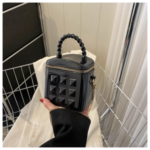 Detail of black glossy mini bag with quilted studs and metallic chain handle