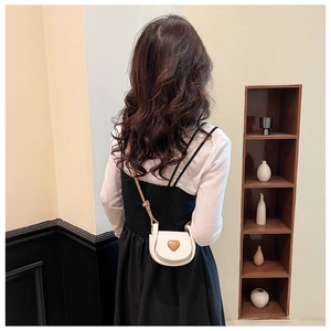 Détail du sac à bandoulière blanc en forme de cœur porté par un mannequin de profil