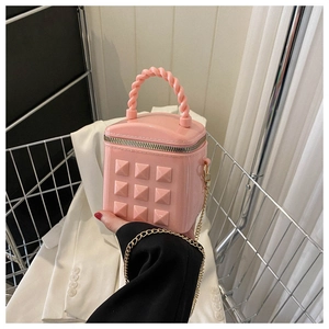 Close-up of pink quilted jelly bag with pyramid studs and elegant golden chain strap