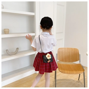 Close-up of children's fashion set featuring a black crossbody bag with floral detail