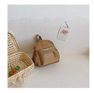 Detailed view of brown nylon toddler backpack with zippered front pocket and leather label