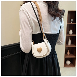 Détail du mini sac à bandoulière blanc avec ornement de cœur et bandoulière réglable