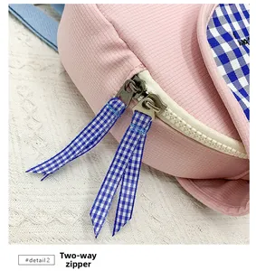 Dettaglio zaino bimbi in velluto rosa con doppia zip e tiranti con motivo a quadretti blu