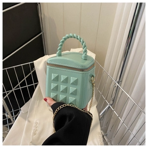 Detail of mint green jelly bag with gold pyramid studs and twisted handle design