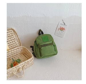 Detail of green kids nylon backpack with GIRL CATS label in a lifestyle home setting