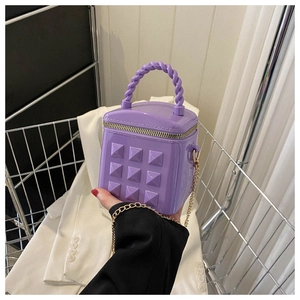 Detailed macro view of purple quilted handbag featuring pyramid studs and gold chain strap