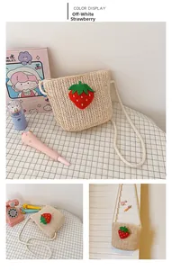 Detail of a beige woven straw bag for girls with a cute 3D strawberry and braided strap