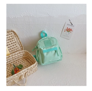 Detail view of a mint green kids backpack with a GIRL CATS rubber logo and a pocket