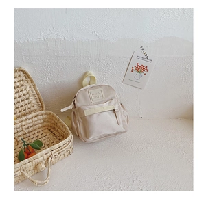 Close-up of beige lightweight nylon kids backpack with decorative straps and leather patch