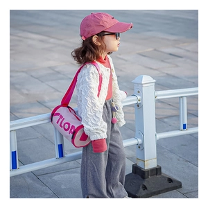 Détail du sac bandoulière cylindrique rose avec lettrage TLOP pour tenue enfant stylée
