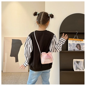 Rear view of a child wearing a pink PU leather mini crossbody bag with a large mesh bow