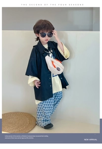 Détail d'un sac bandoulière beige en toile pour enfants avec fermeture éclair orange vif