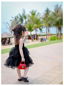Kleines Mädchen im schwarzen Tutu mit roter herzförmiger Jelly-Tasche und Goldkette