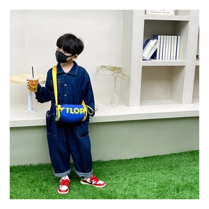 Détail du sac bandoulière cylindrique bleu pour enfant avec lettres TLOP jaunes