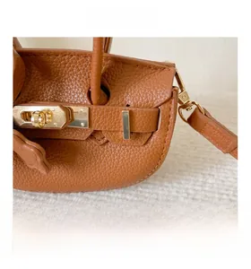 Gros plan du fermoir tournant doré et du cuir grainé sur le sac à main marron