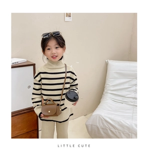 Close-up of a brown mini flap crossbody bag paired with a beige knitted toddler outfit