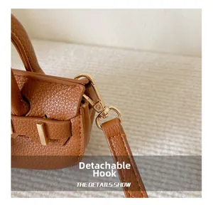 Détail d'un sac à main en cuir marron grainé avec un crochet doré amovible et quincaillerie