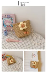 Detail of girls straw crossbody bag featuring a yellow cloth flower and orange pompoms
