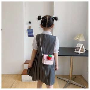 Rear view of a girl wearing a pink PU leather mini bag with glitter and strawberry detail
