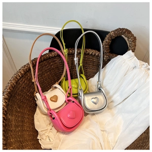 Détail de mini sacs à bandoulière colorés en forme de cœur dans un panier tressé