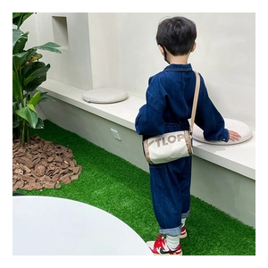 Détail du sac cylindrique en toile pour enfants avec garniture en cuir et motif de lettres